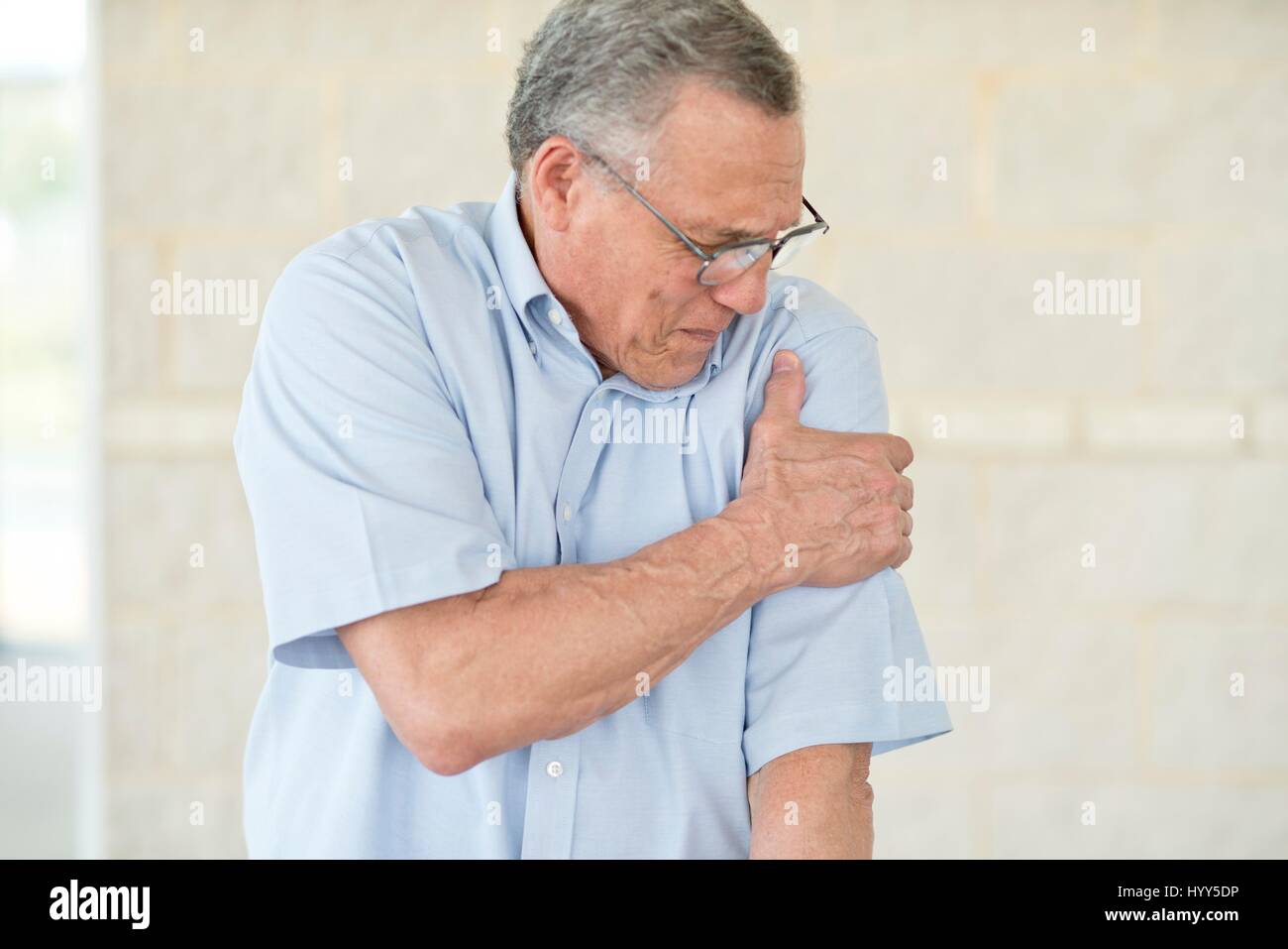 Ältere Mann hält seinen linken Arm Schmerzen. Stockfoto