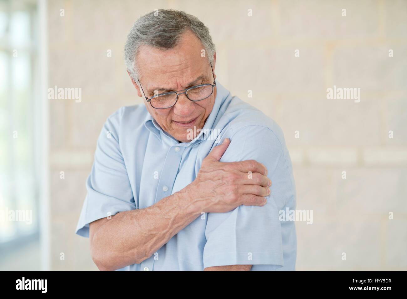 Ältere Mann hält seinen linken Arm Schmerzen. Stockfoto