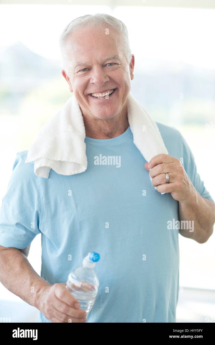 Senior Woman im Fitnessraum mit Wasserflasche und Handtuch. Stockfoto