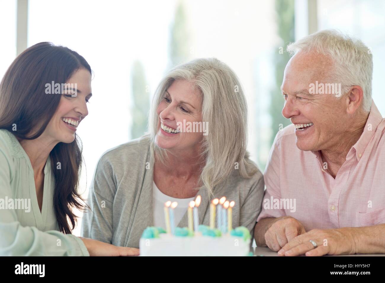 Älteres Paar und Erwachsene Tochter mit Geburtstagstorte. Stockfoto