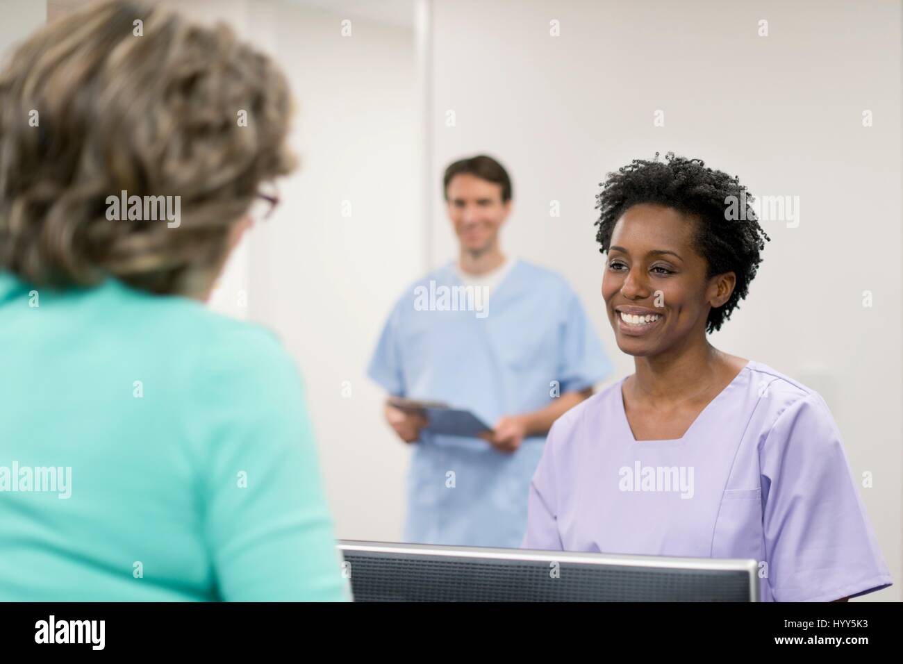 Krankenschwester lächelnd gegenüber weiblichen Patienten. Stockfoto