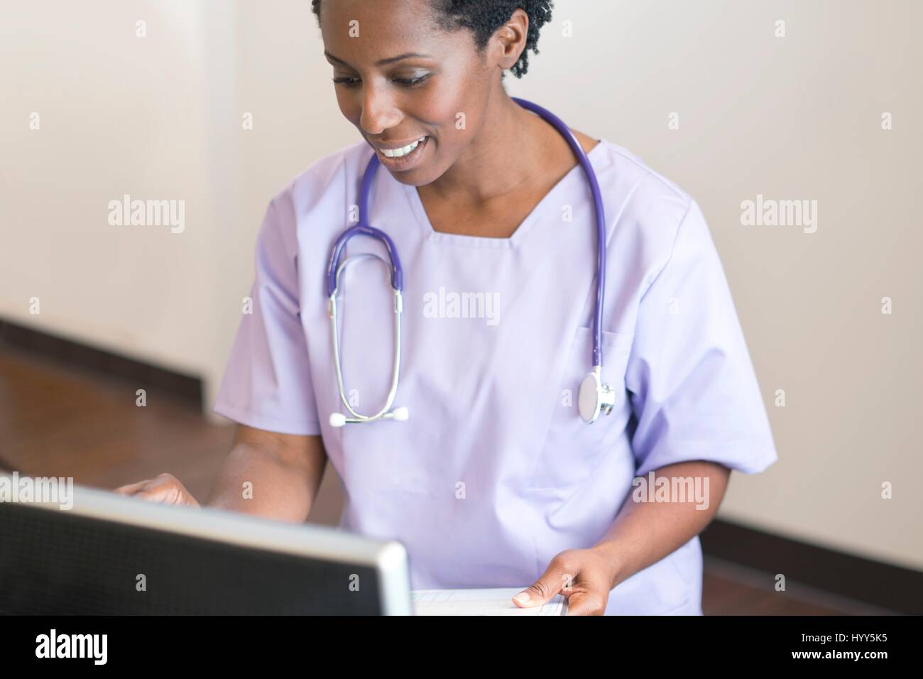 Krankenschwester mit Computer, lächelnd. Stockfoto