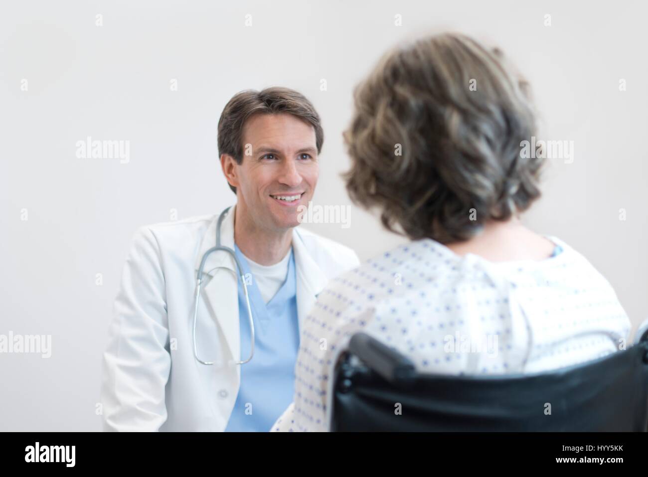 Männlichen Arzt lächelnd an Reife weibliche Patienten im Rollstuhl. Stockfoto