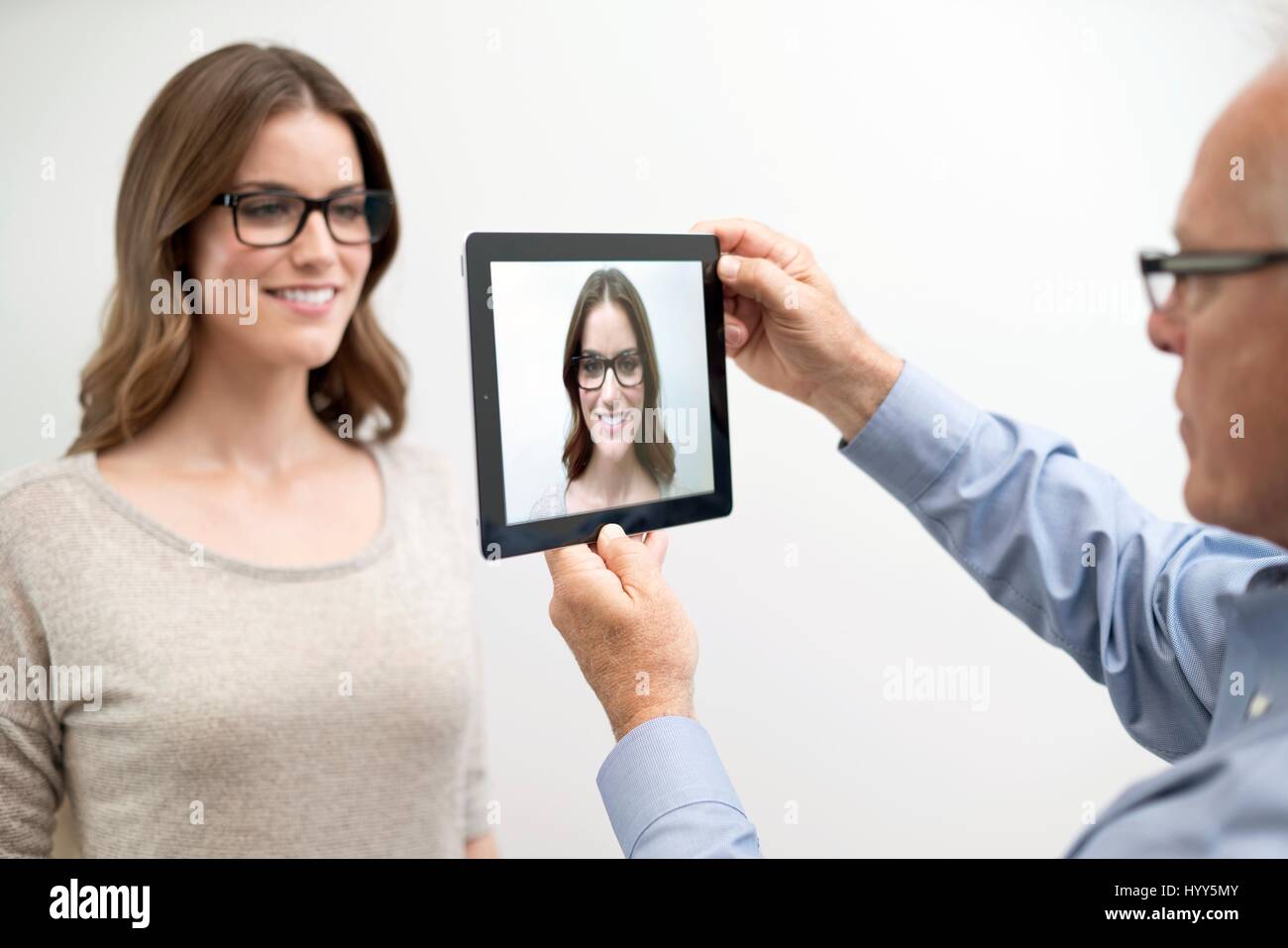 Mann, der digital-Tablette vor Frau ins Gesicht hält. Stockfoto