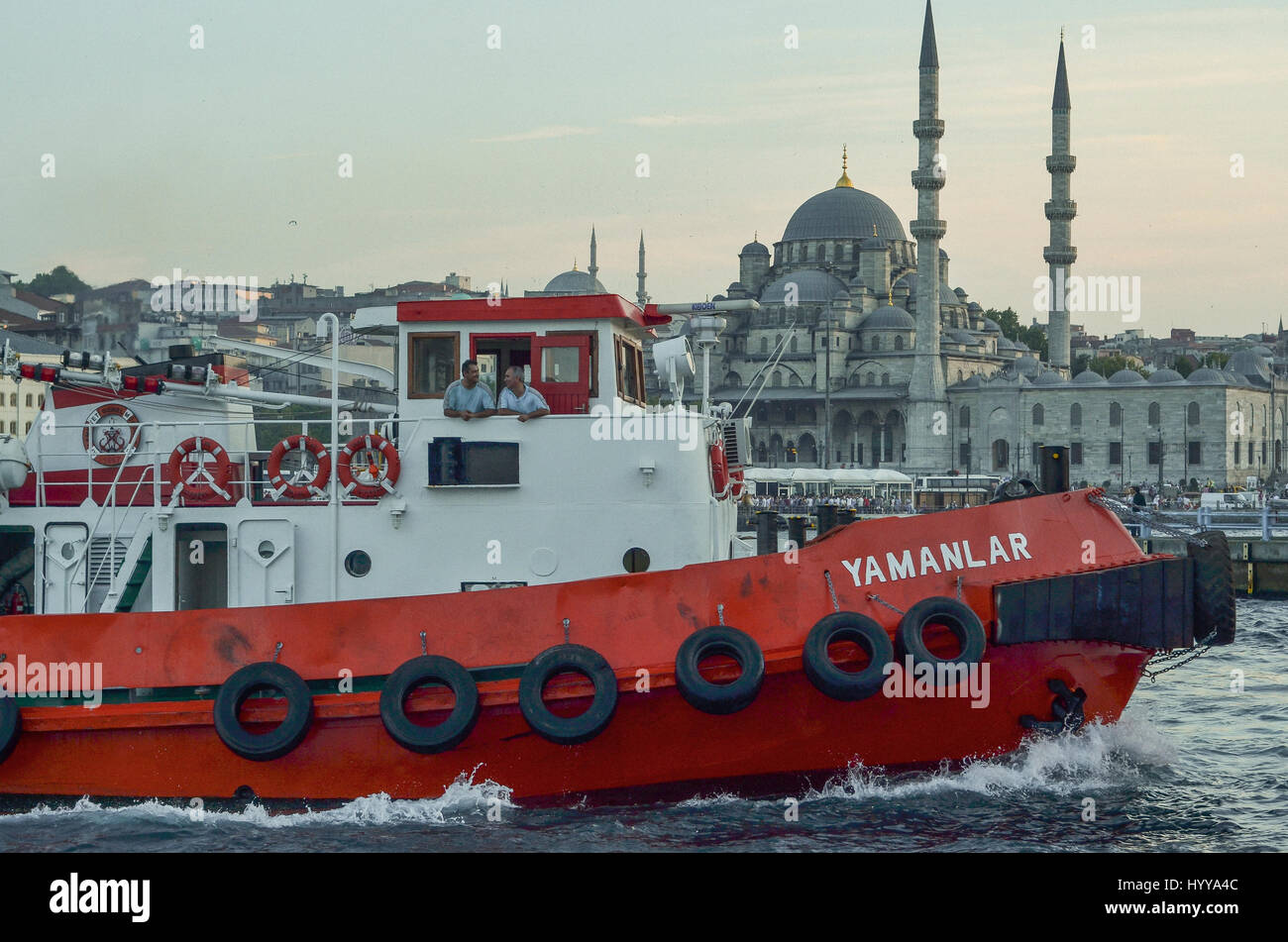 Ein Schlepper fährt in das Goldene Horn in der Abenddämmerung.   Die neue Moschee (Yeni Camii) können im Hintergrund zu sehen. Stockfoto