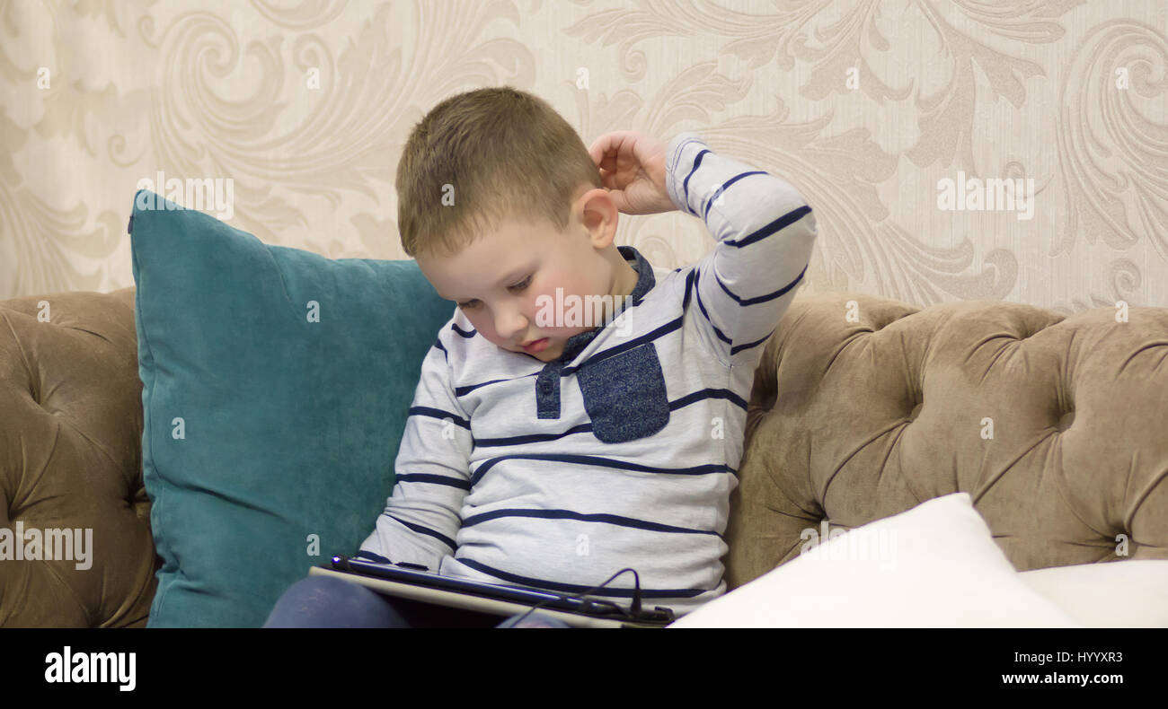 Junge auf der Couch sitzen und mit Blick auf tablet Stockfoto