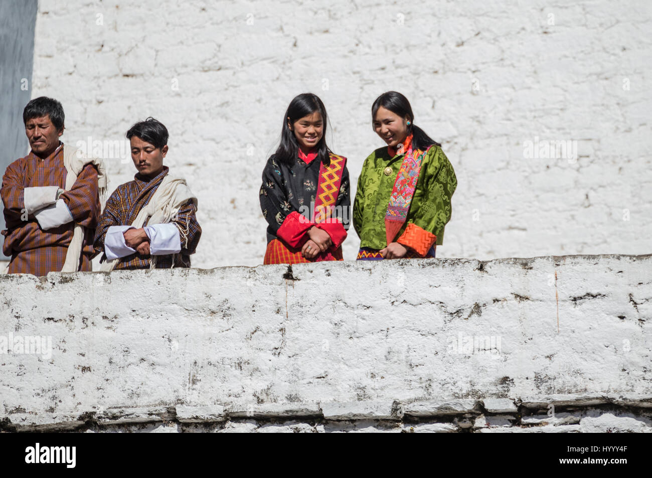 Männer in Gho und Frauen in Kira beobachten ein Tsechu (Bhutan) Stockfoto