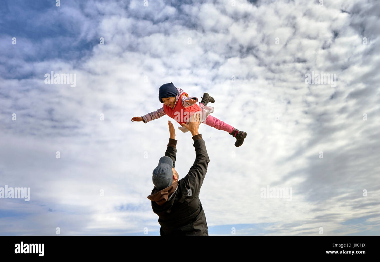 Vaterschaft, Familie und Elternschaft Konzept - glücklich lächelnden jungen Vater mit Baby über blauen Himmel Stockfoto