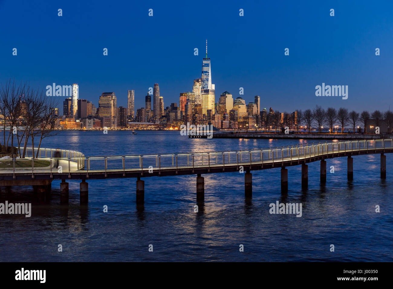 New York City-Financial District Wolkenkratzer bei Sonnenuntergang und Hudson River von Hoboken Promenade. Lower Manhattan Skyline und Fußgängerbrücke Stockfoto
