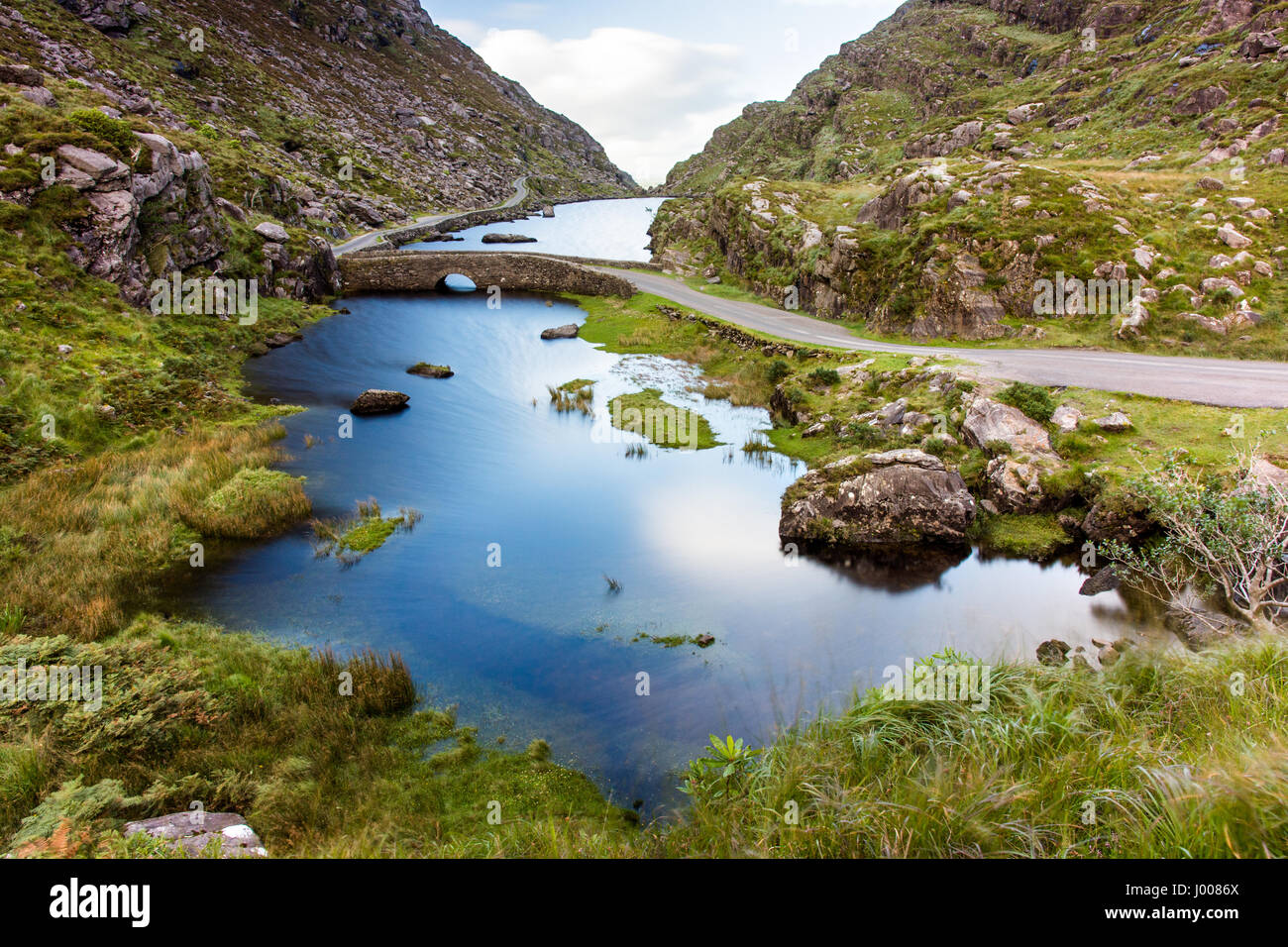 Der Fluss Loe & schmale Straße Bergwind durch das Gap of Dunloe-Tal, eingebettet in die Macgillycuddy riecht nach Bergen der irischen Grafschaft Kerry. Stockfoto