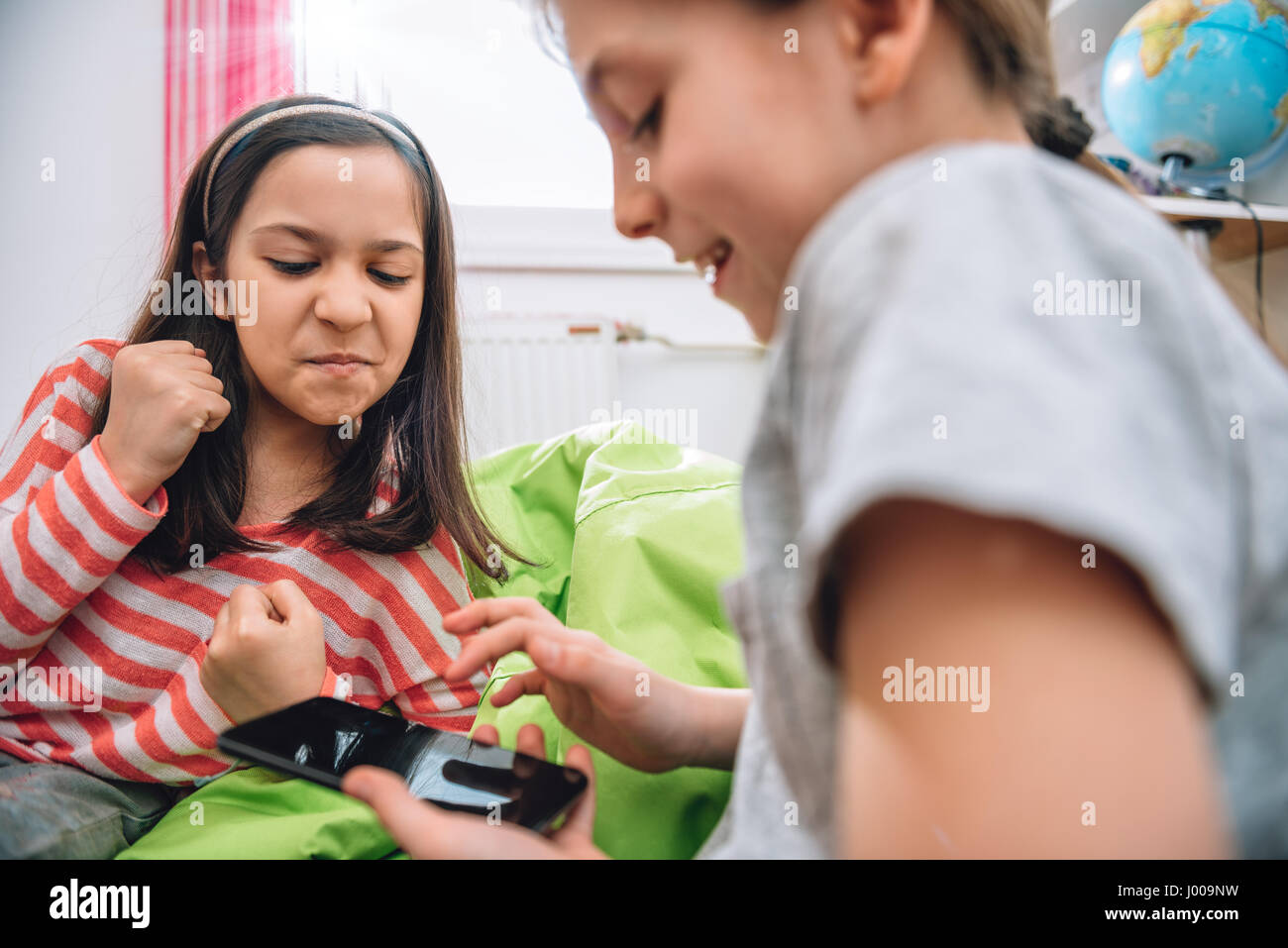 Zwei Mädchen sitzen im Kinderzimmer und mit Smartphone Stockfoto