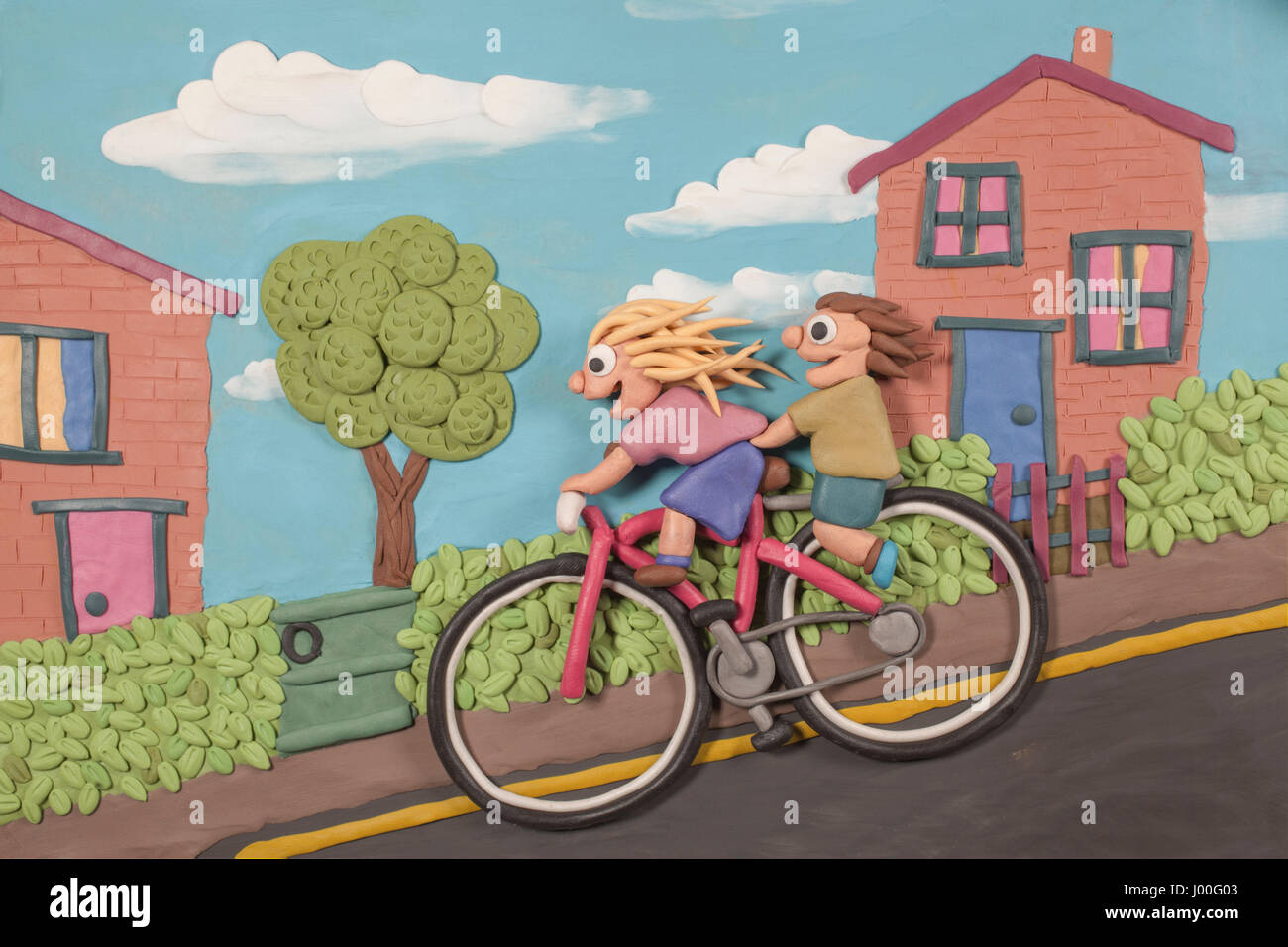 Modellieren Ton Abbildung von zwei Kindern, die einen Hang hinunter auf einem großen Fahrrad Freilauf Stockfoto