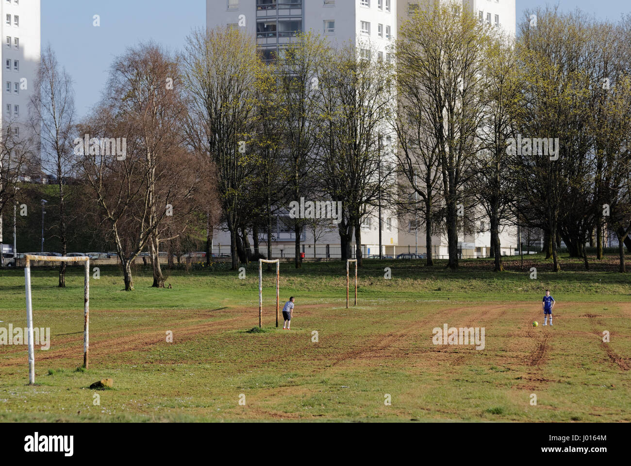 Blairdardie Park keal Avenue wo kleine Jungen während der Osterferien Spiegeln Ostern Fußball spielen im Schatten der Projekte Stockfoto