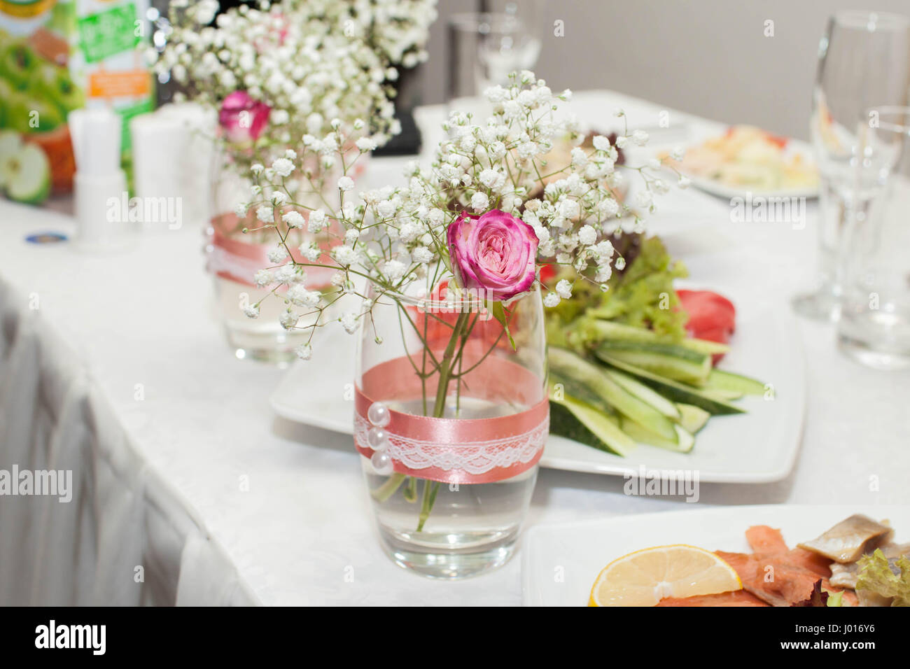 Glas mit Rosen und Schleierkraut. Hochzeitsdekorationen. Close-up Stockfoto