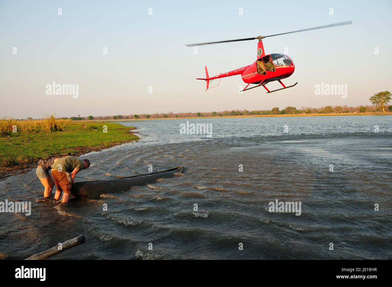 Hubschrauber über dem Fluss mit Boot vor dem Untergang retten Menschen Stockfoto