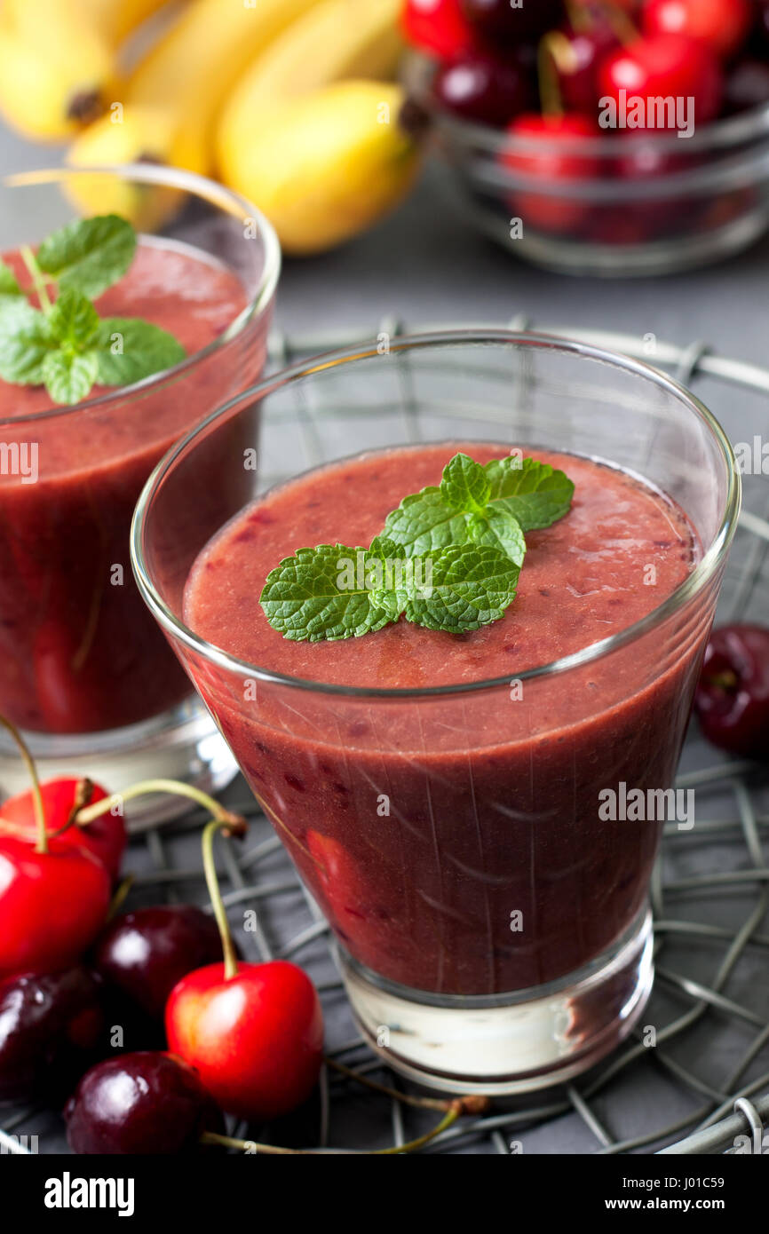 Smoothie mit Kirsche und Banane in ein Glas, eine Mischung von Süßkirschen auf konkrete Hintergrund Stockfoto