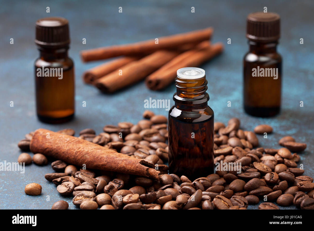 Glasflaschen mit ätherischen Ölen von Kaffee und Zimt auf blauem Hintergrund Stockfoto