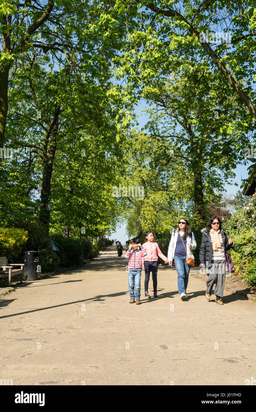 Eine asiatische Familie, die einen Hügel in Horniman Gardens, Forest Hill, London, SE23, Großbritannien, hinunterläuft Stockfoto