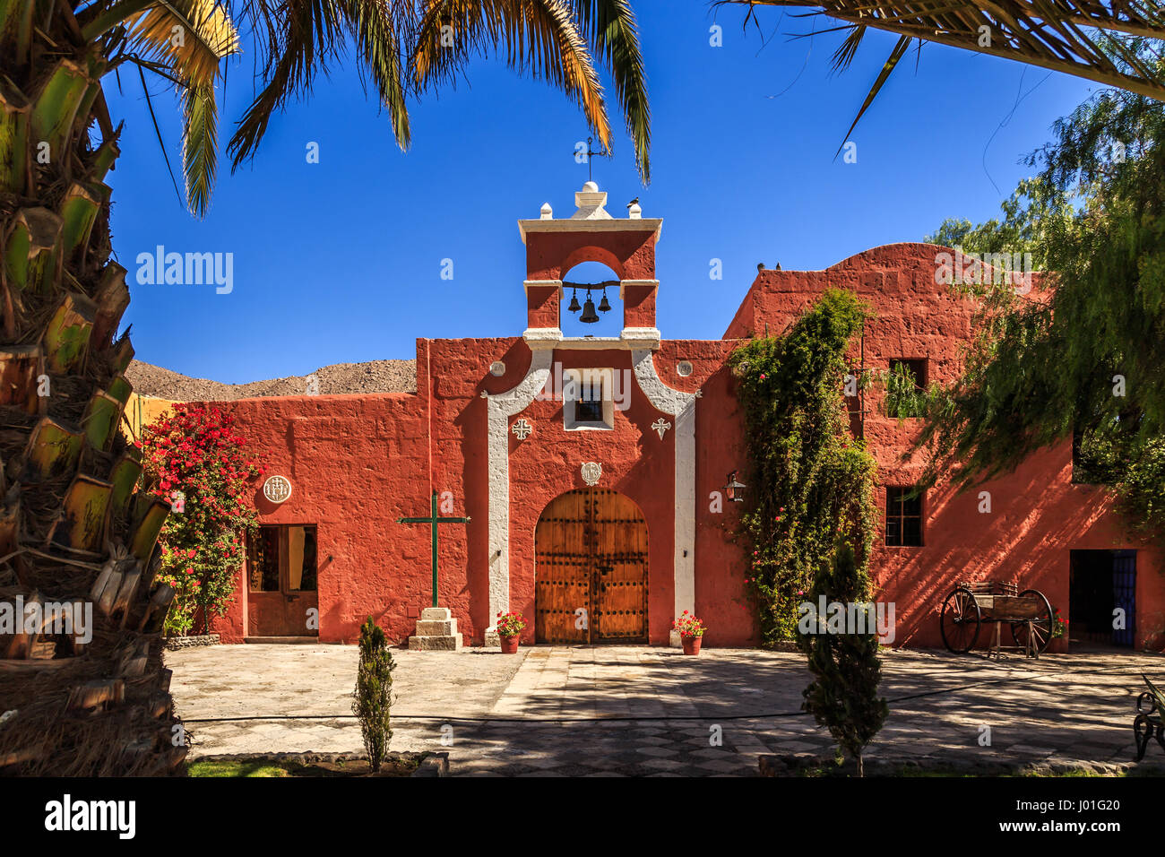 Rote Wände der spanischen katholischen Kapelle mit Palmen, Bäumen und Blumen, Arequipa, Peru Stockfoto Rote Wände der spanischen katholischen Kapelle mit Palmen, Bäumen und Blumen, Arequipa, Peru Stockfoto