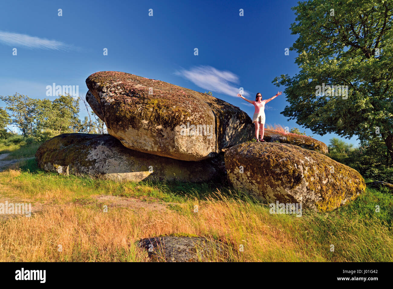 Frau steht auf riesigen Felsen mit ausgestreckten Armen Stockfoto