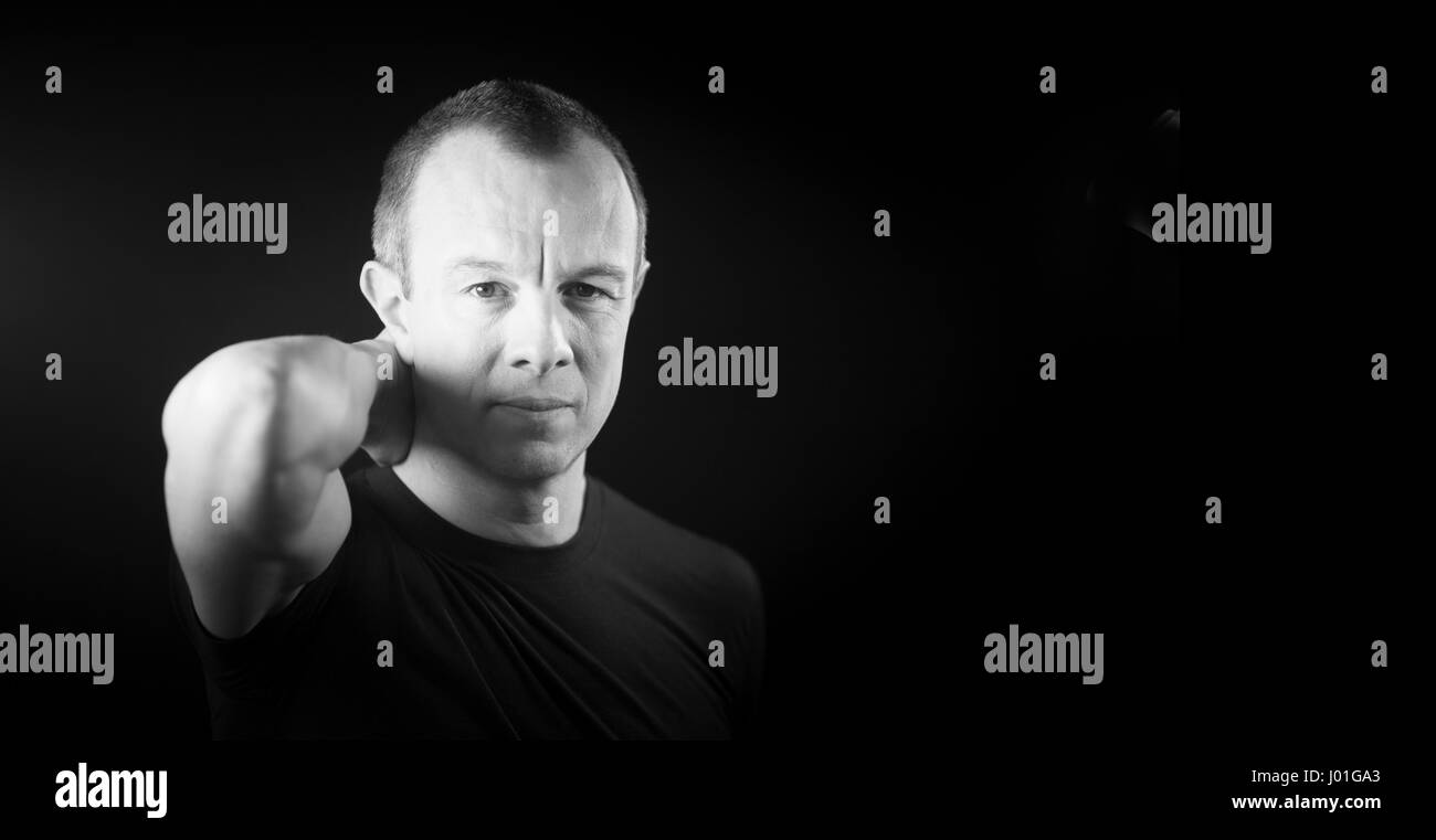 Attraktive hübscher schlanke gesunde Mann im Alter von in 40er Jahren in schwarzes T-shirt gegen schlicht schwarz Studio Portrait-Hintergrund. Stockfoto
