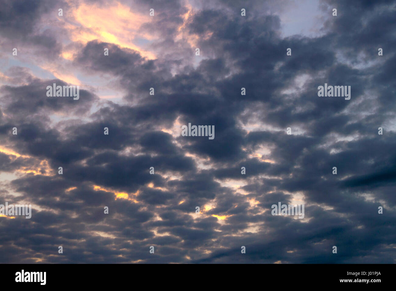 Dunkle, wispy Wolken verdecken teilweise ein blauer Himmel und farbenprächtigen Sonnenuntergang Stockfoto