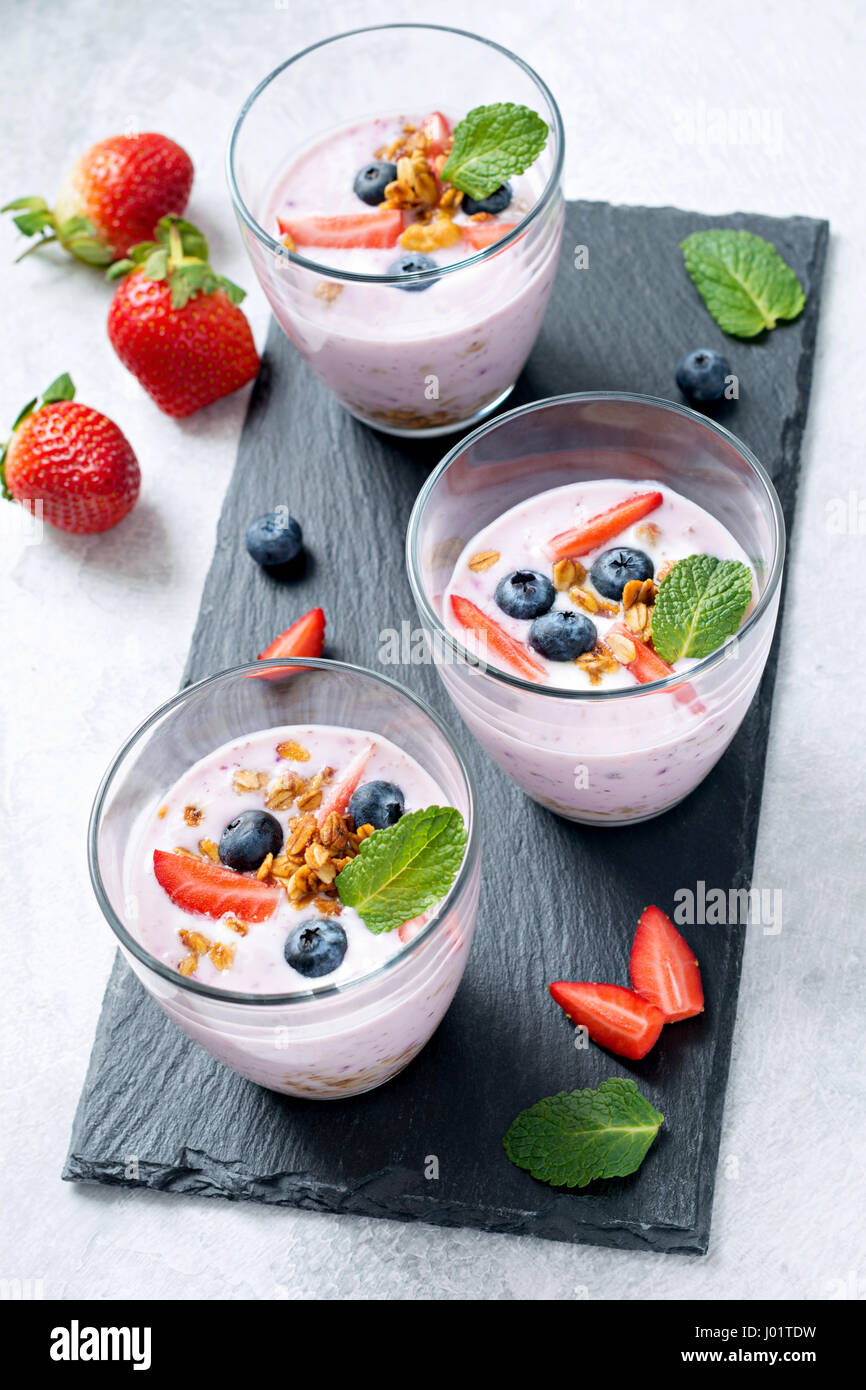 Joghurt-Frucht-Smoothie mit frischen Erdbeeren, Heidelbeeren und Müsli Stockfoto