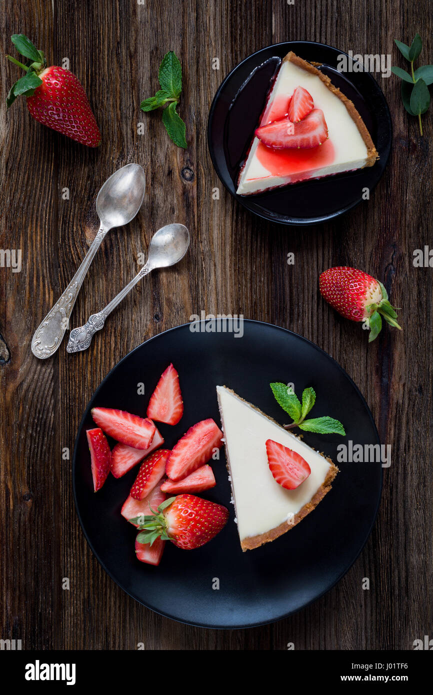 Erdbeer-Käsekuchen auf schwarzen Druckplatte über rustikalen hölzernen Hintergrund. Ansicht von oben Stockfoto