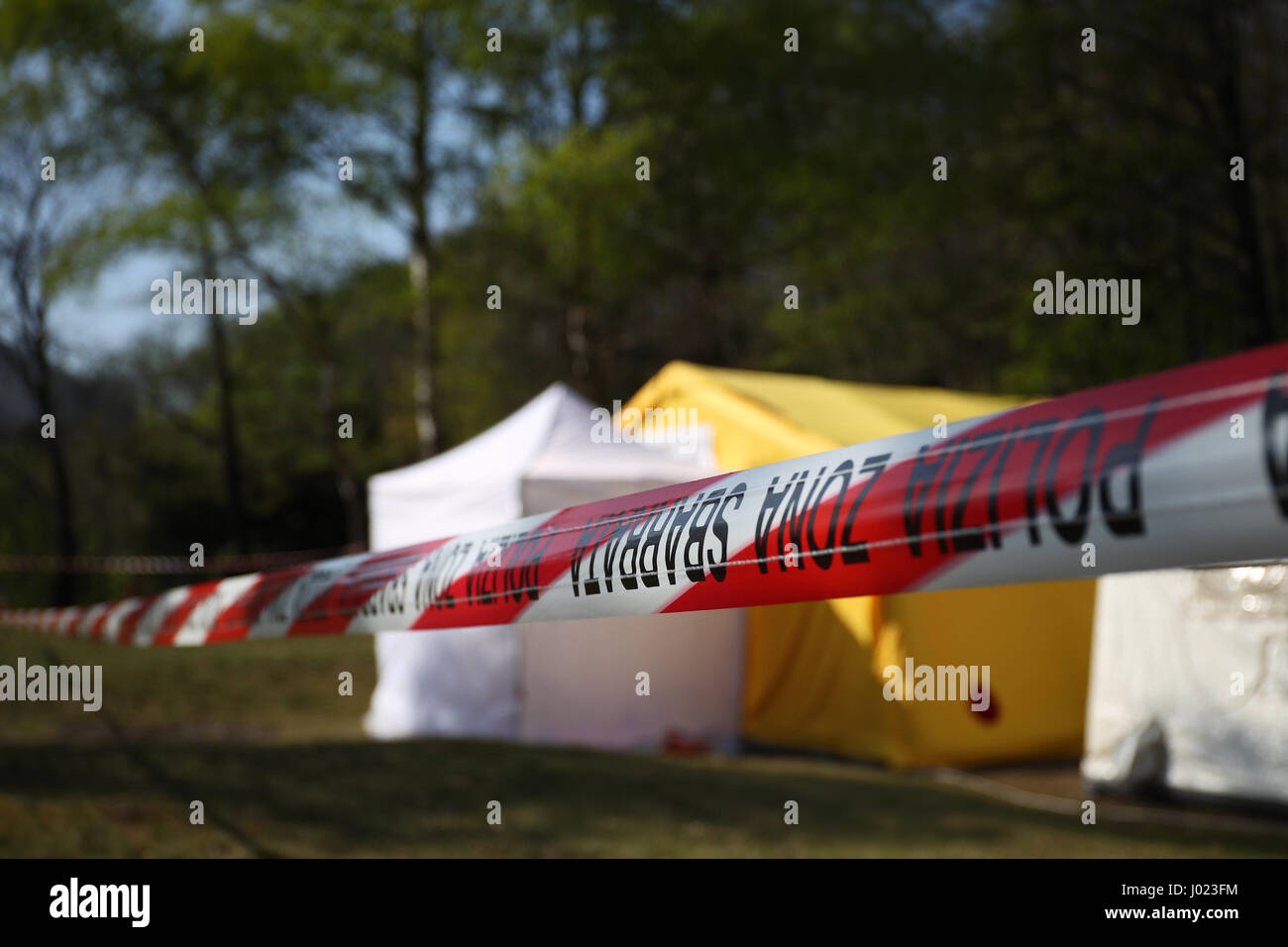 Rote und weiße Polizeiabsperrung um ein Verbrechen-Szene-Zelt in einem Wald Stockfoto