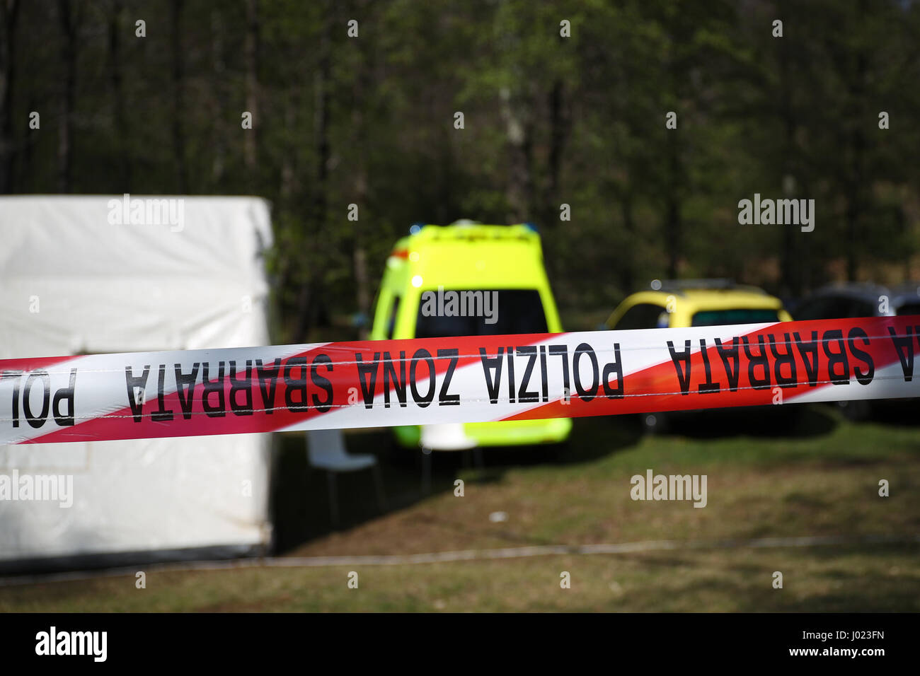 Rote und weiße Polizeiabsperrung um ein Verbrechen-Szene Zelt in einem Wald mit Krankenwagen, Polizei und Gerichtsmedizin Fahrzeuge Stockfoto