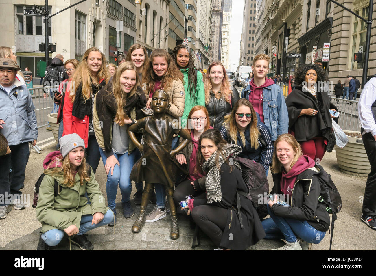 Touristen posiert mit furchtlosen Mädchen Statue starrte die Aufladung Wall Street Bull, NYC, USA Stockfoto