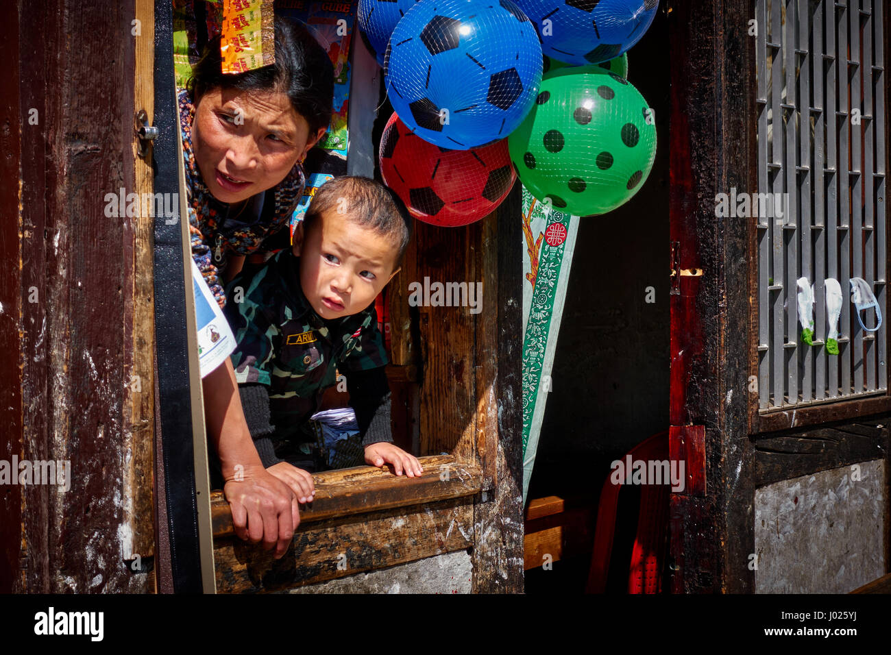 Mutter und Sohn schauen aus dem Fenster ihrer Doma Shop in Thimphu, Bhutan Stockfoto