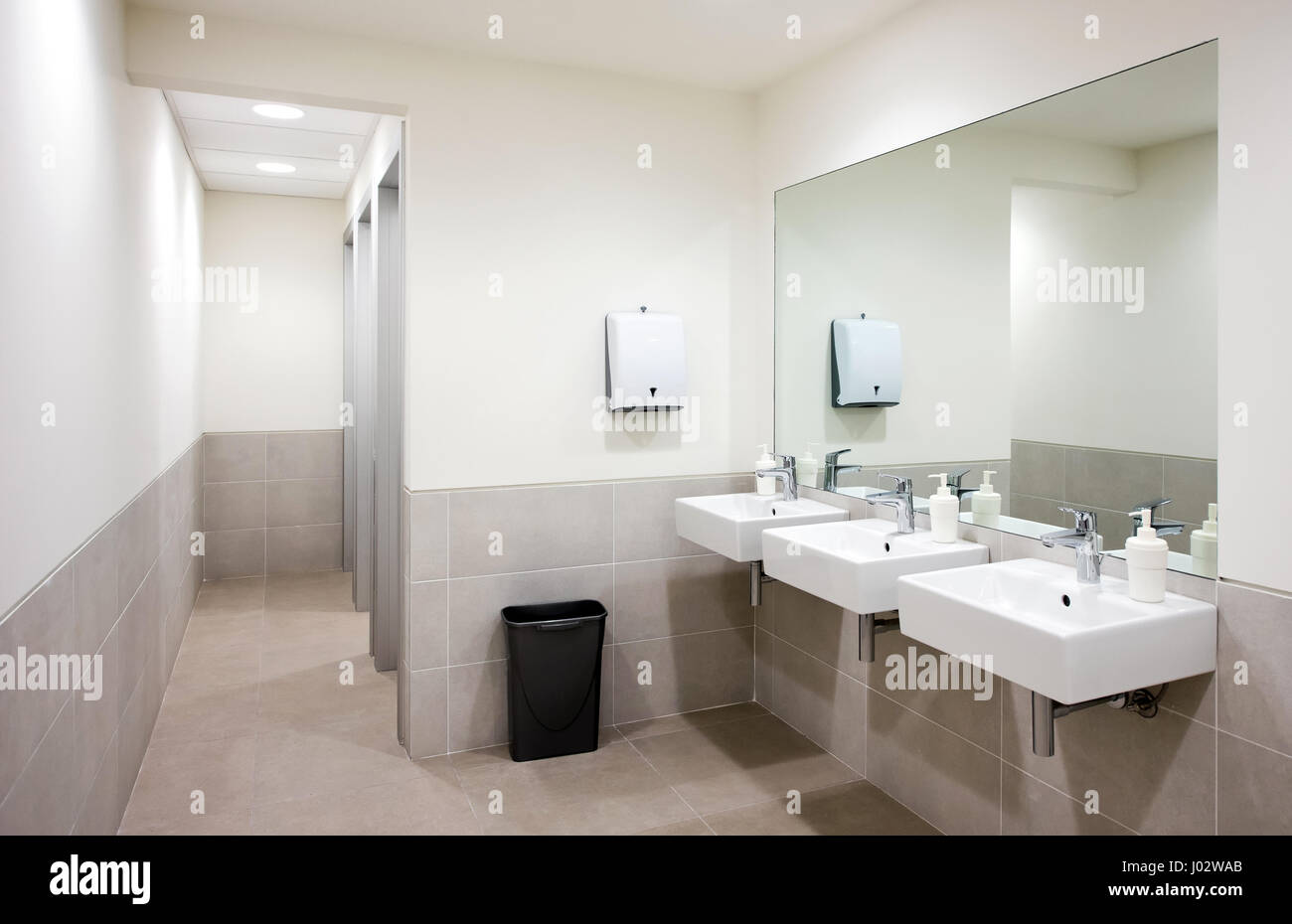 Leere öffentliche Bad mit weißen Wannen und große Wandspiegel, Hand Luft trockener und schwarzen Papierkorb Stockfoto