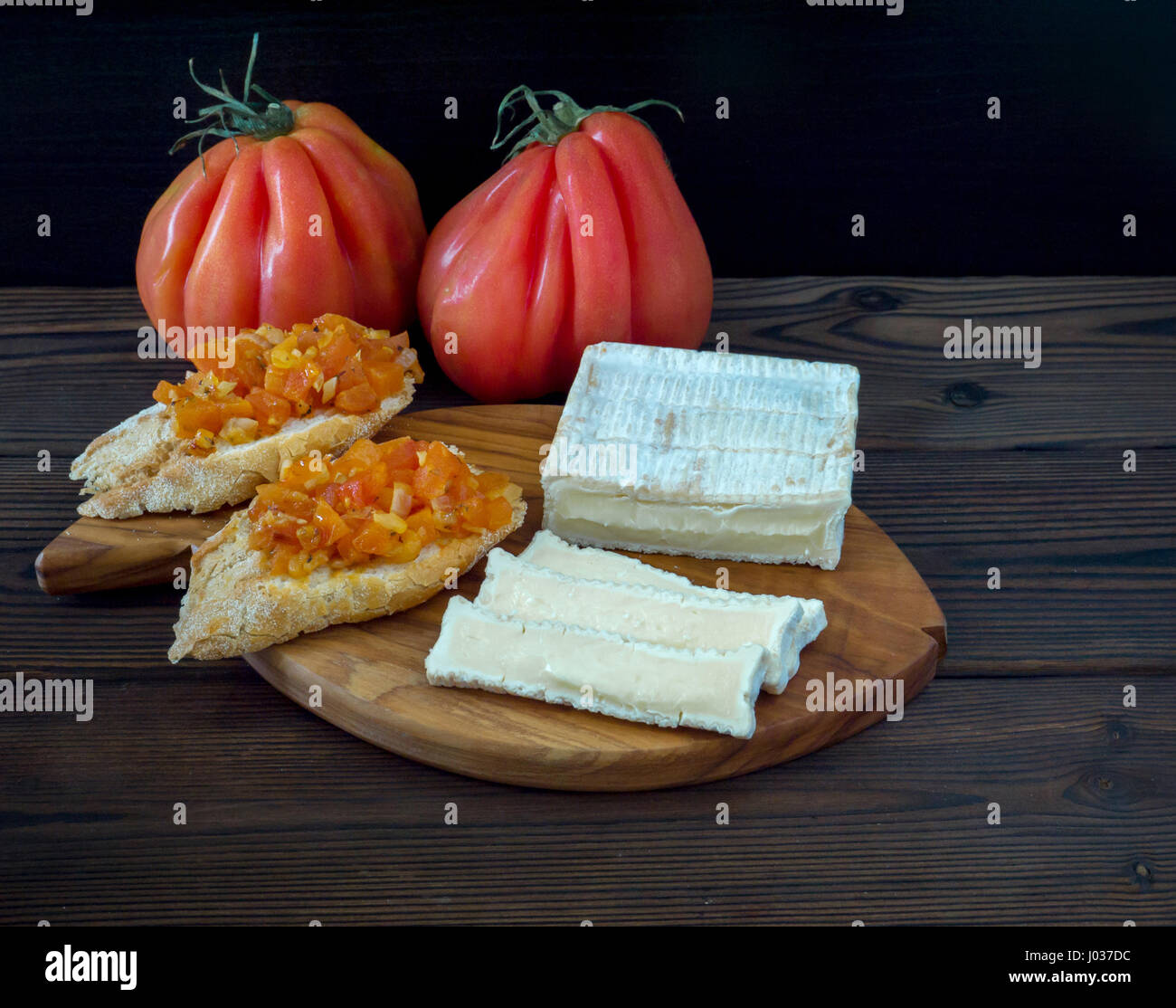 Ziegel geformt, weißen Schimmel Käse, reife Tomaten und Toast auf die strukturierte Holzbrett Stockfoto