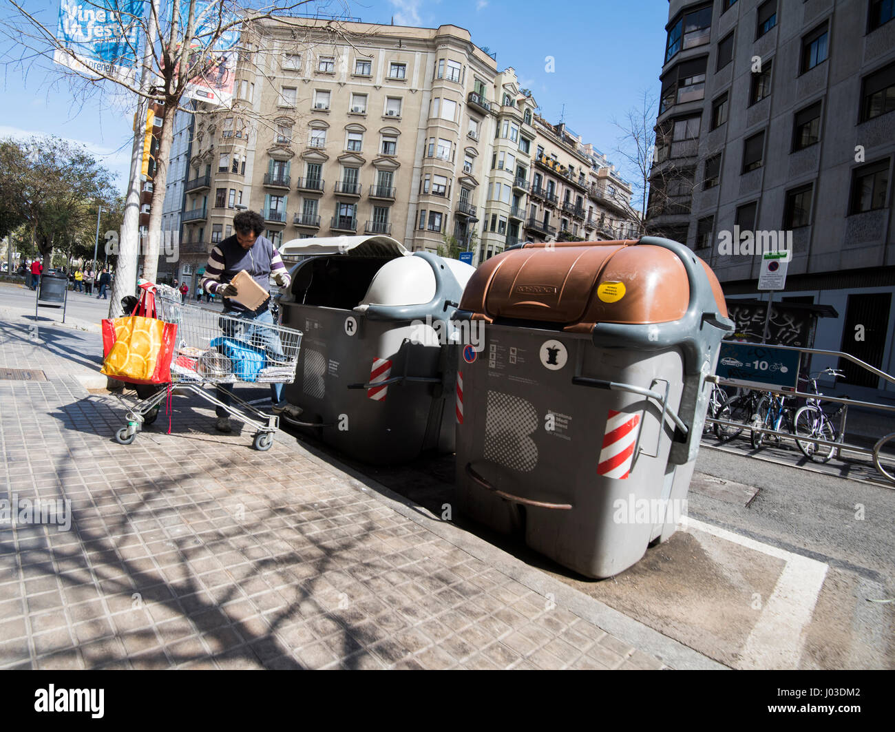 Mann auf der Suche durch den Inhalt einer Mülltonne auf einer Straße in Barcelona, Spanien-Europa-EU Stockfoto