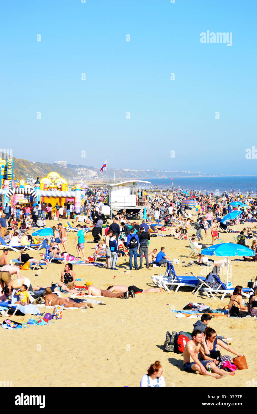 Menschen, die zum Sonnenbaden am überfüllten Strand von Bournemouth an einem heißen Tag im April, Dorset, Großbritannien Stockfoto
