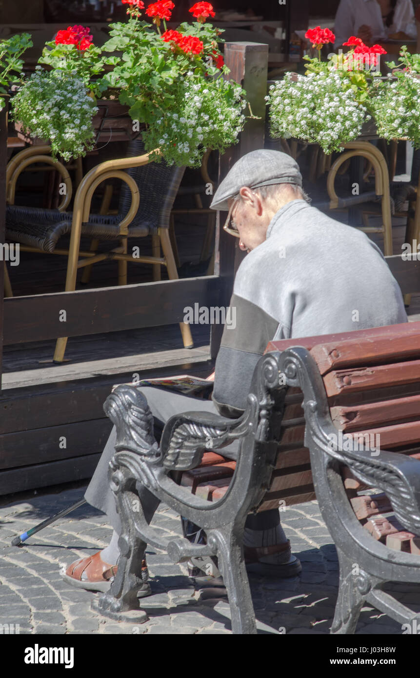 Alter Mann auf der Bank auf der Straße lesen. Stockfoto