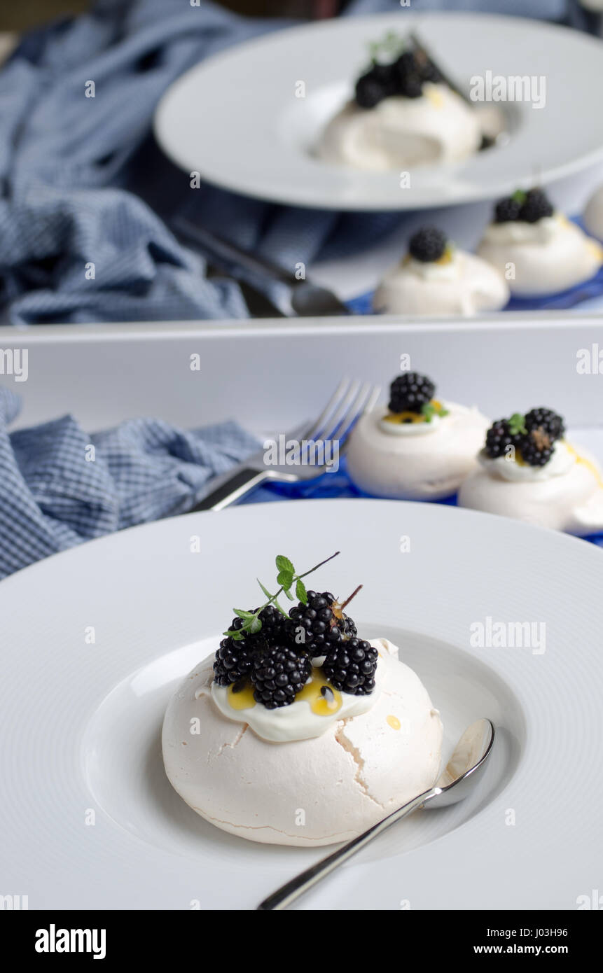 Pavlova-Dessert mit Passionsfrucht-Sauce und Waldbeeren. Pastell-Farben. Stockfoto