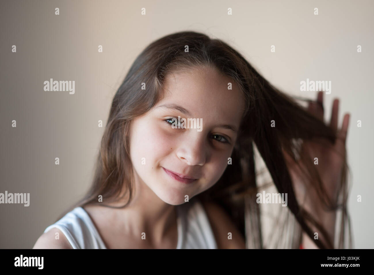 kleines Mädchen lächelnd streckt ihr Haar mit einer hand Stockfoto