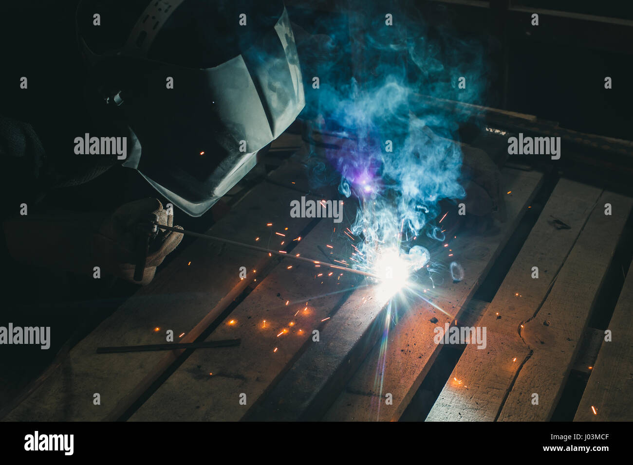 Der elektrische Schweißer erledigt die Arbeit in der Fabrik. Arbeiter in spezielle Schutzausrüstung Stockfoto