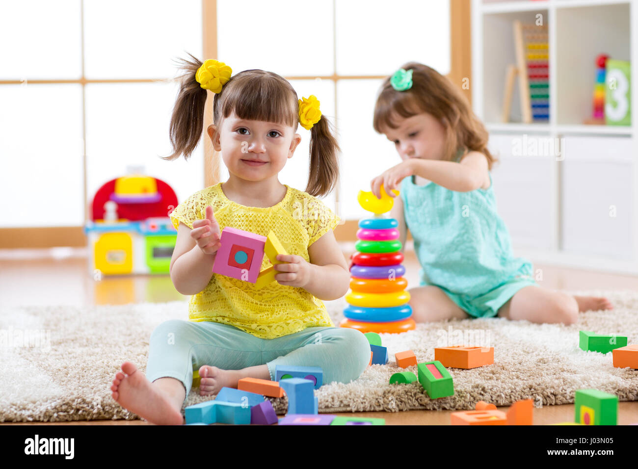 Kinder spielen mit Bausteinen zusammen. Pädagogische Spielwaren für Vorschule und Kindergarten Kind. Kleine Mädchen bauen Spielzeug daheim oder Kindertagesstätten. Stockfoto