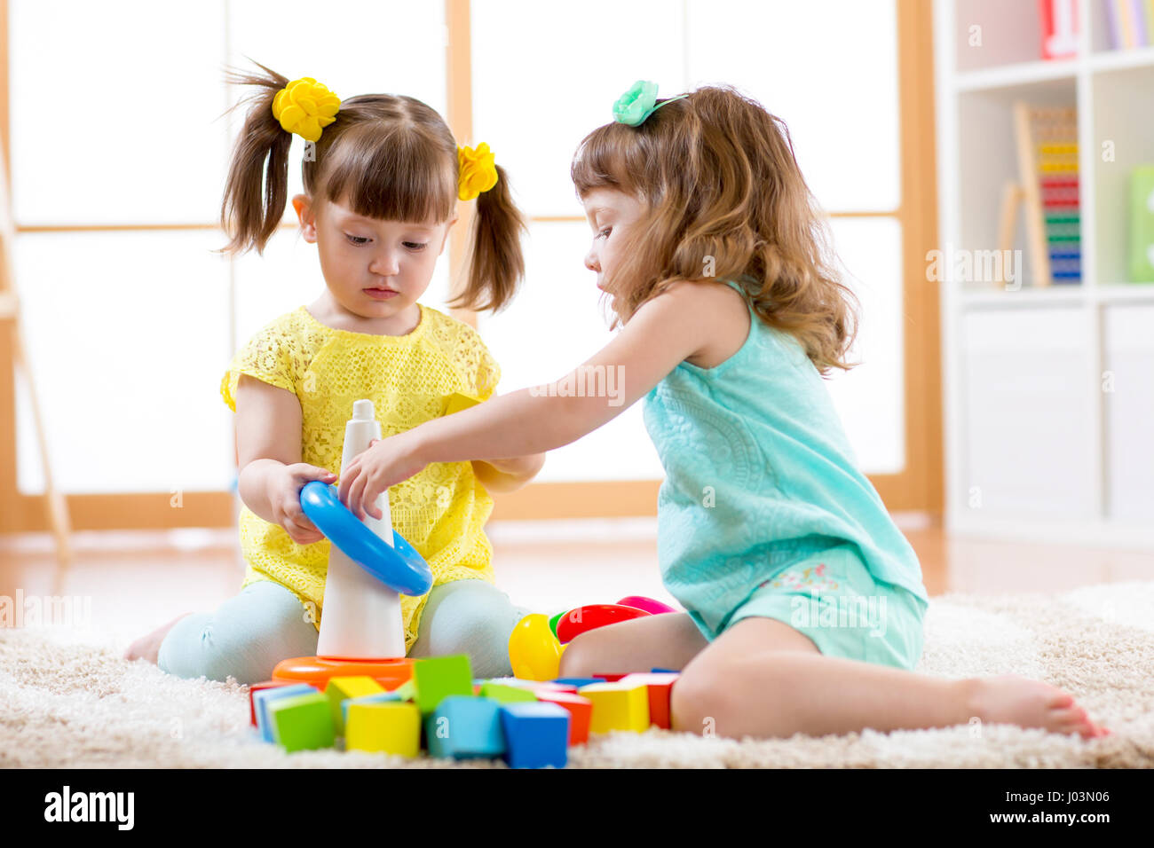 Kinder spielen zusammen. Baby und Kleinkind Kinder spielen mit Blöcken. Pädagogische Spielwaren für Vorschule und Kindergarten Kind. Kleine Mädchen bauen Pyramide Spielzeug daheim oder Kindertagesstätten. Stockfoto