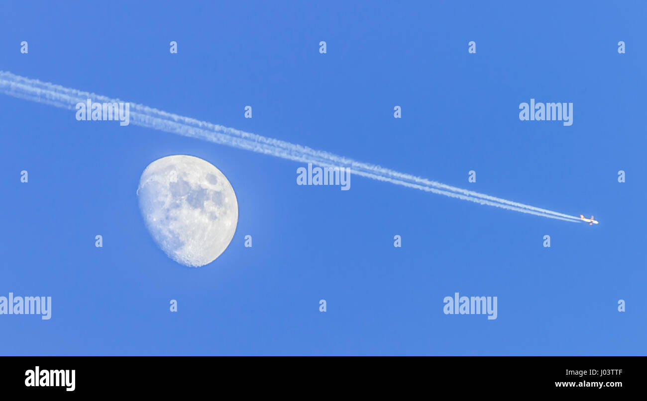 Mond im Waxing Crescent Phase mit einem Flugzeug erscheinen zu übergeben, zeigt Kondensstreifen und blauer Himmel. Stockfoto