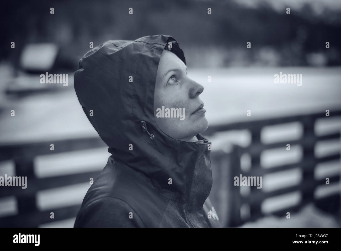Schöne Frau mit Kapuzenjacke im freien blickte zum Himmel, monochromen Bild Stockfoto