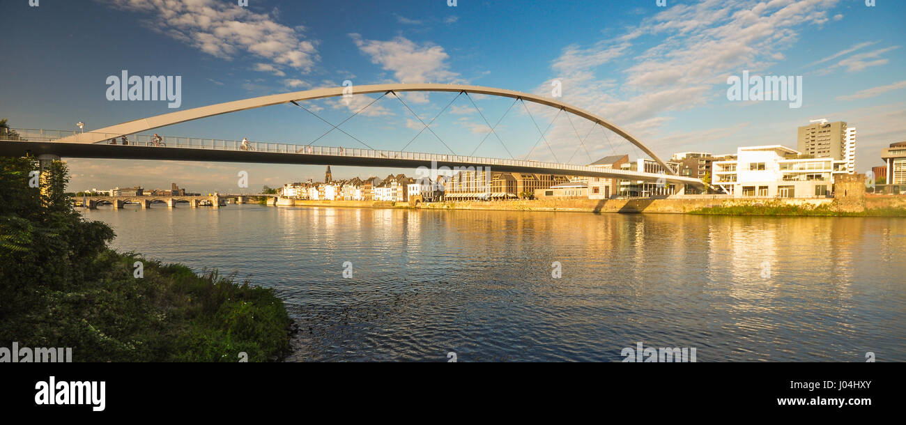 Abendlicht beleuchtet das Stadtbild von Maastricht in den Niederlanden, einschließlich der Maas und der hochrangigen Fußgängerbrücke, De Hoge Brug. Stockfoto