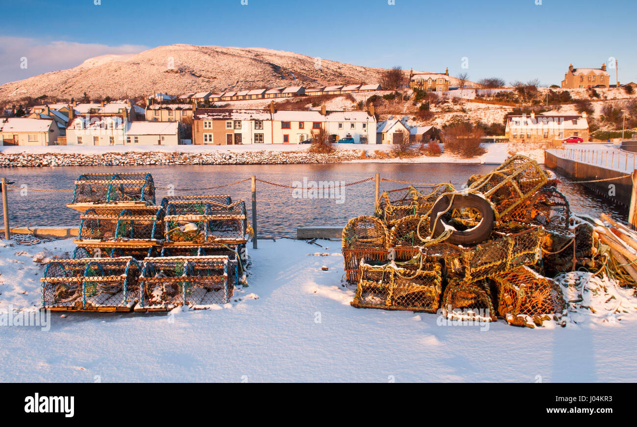 Hummer-Töpfe liegen unter den unberührten Schnee auf dem Deich von Helmsdale Hafen an der Moray Firth von Sutherland in den Highlands von Schottland. Stockfoto