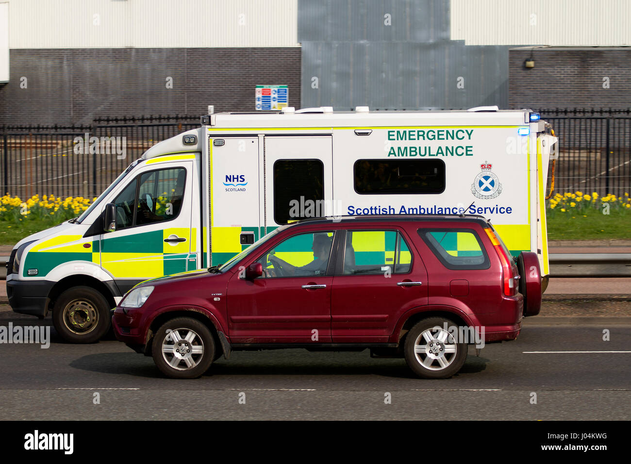 Ein schottischer Krankenwagen-Service entsteht Krankenwagen, der ein Auto überholt, das auf einen Notfall entlang der zweispurigen Kingsway West in Dundee, Schottland, reagiert Stockfoto