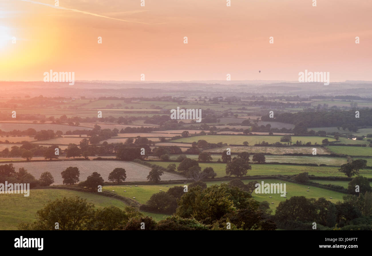 Die Sonne über einem Flickenteppich aus Weide, Felder, Feldfrüchte und Wäldern im Blackmore vale Landwirtschaft Stadtteil North Dorset, aus bulbarrow Hill gesehen Stockfoto