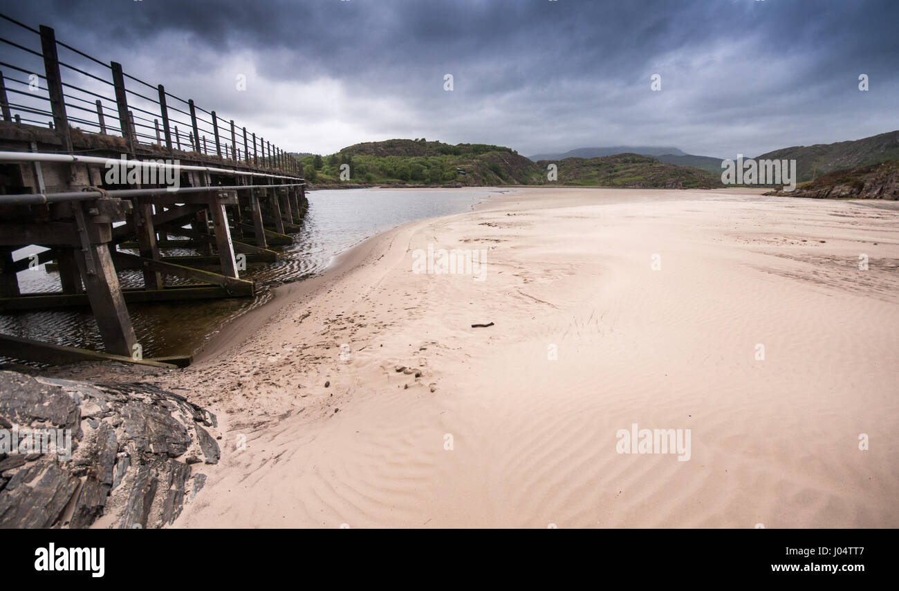 Die alte Pont Briwet Brücke über der Mündung des Flusses Afon Dwyryd unter den Bergen von Snowdonia und inmitten der sandigen Strände von der Küste von North Wales Stockfoto