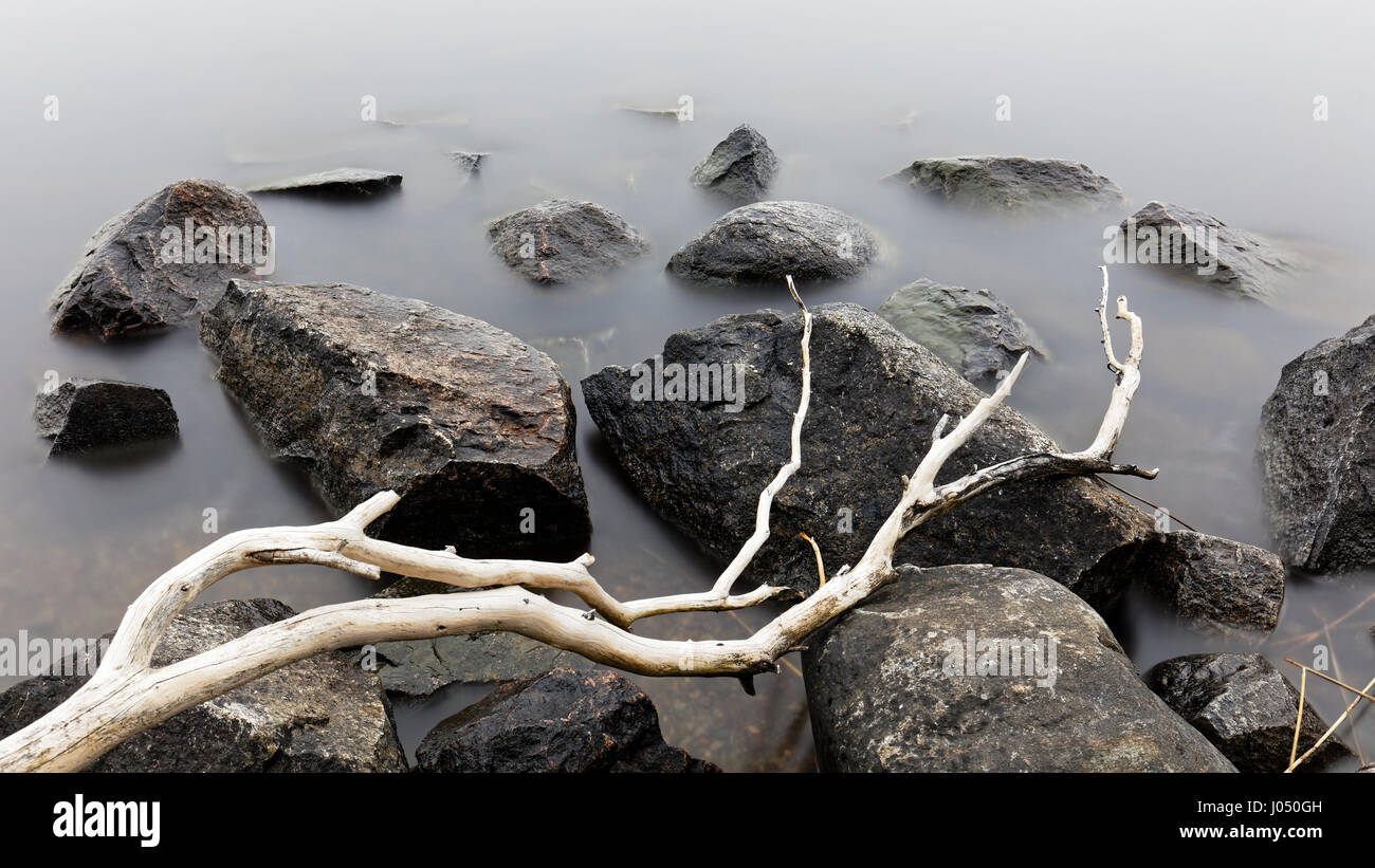 Milchiges Wasser um Steinen einer Küste in der Nähe von Vaxholm, Schweden Stockfoto